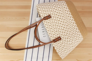 Detail of bohemian woven tote bag showing leather handles and rivet stitching texture