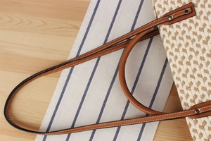 Detail of hand-woven shoulder bag showing premium leather strap with contrast stitching
