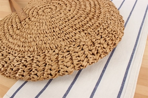 Detailed macro view of woven paper rope texture and leather handle with X-shaped stitching