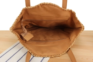 Detail showing the inner lining of straw tote bag with zipper pocket and main compartment