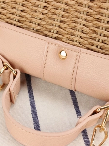 Détail d'un sac de plage tressé en papier avec bordure en similicuir rose et rivets dorés