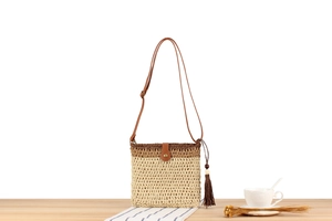 Detailed close-up of woven crossbody bag with brown tassel and leather strap