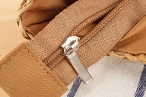 Detail of silver metal zipper closure and brown lining on woven paper rope beach bag