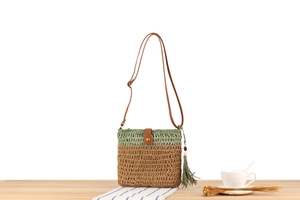 Detail of green and beige woven crossbody bag with brown tassel and wooden beads decoration
