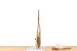 Detail of hand-woven crossbody bag with brown leather strap and tassel charm