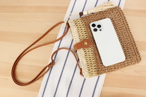 Detail view of straw woven crossbody bag with leather strap and tassel ornament