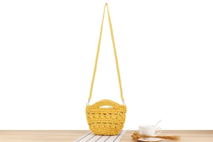 Détail du mini sac seau tressé jaune avec motifs à fleurs et longue bandoulière