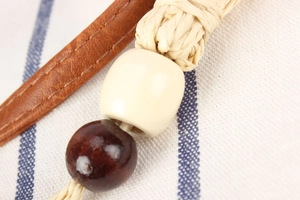 Close-up of handmade woven straw bag with decorative wood beads and leather strap