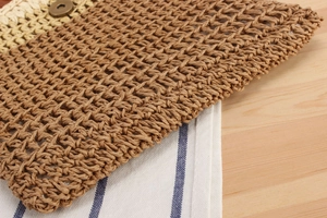 Detail of hand-woven straw bag with two-tone texture and vintage metal snap closure