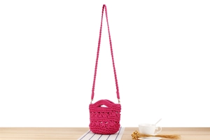 Détail d'un sac seau rose magenta tissé main avec texture crochet et poignée ronde