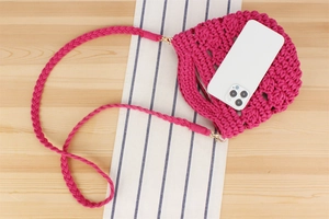 Vue détaillée du mini sac seau crocheté magenta montrant la texture tissée et la taille
