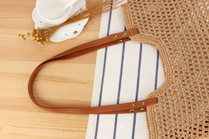Détail d'un sac cabas en coton tressé avec des anses en similicuir marron et rivets