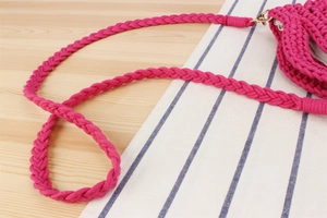 Détail de la bandoulière en crochet rouge rose avec fermoir doré pour sac de paille