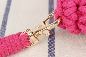 Gros plan détaillé d'un sac tissé rose avec fermoir mousqueton en métal doré et texture