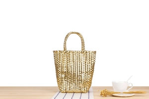 Détail d'un sac à main tissé doré avec texture en maille sur une table en bois chic
