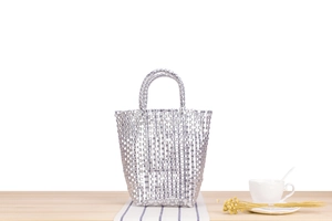 Détail d'un sac à main tissé argenté sur une table en bois avec décor élégant