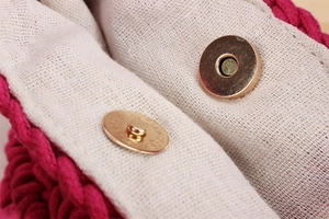 Gros plan du sac seau tissé rose fuchsia avec fermoir magnétique et doublure beige