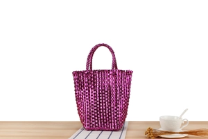 Détail d'un sac cabas fuchsia tissé à la main avec de larges poignées sur une table