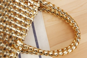 Gros plan sur la texture tressée dorée et les poignées élégantes de ce sac à main chic