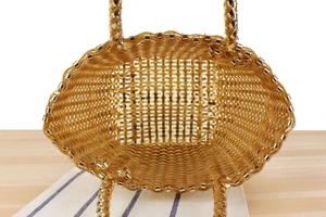 Vue détaillée du sac panier tressé doré avec une texture brillante de haut en bas