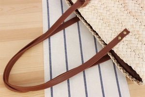 Detail of woven straw bag with premium brown leather strap and rivet reinforcements