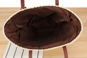 Interior view of straw tote bag with brown canvas lining, zipper closure and inner pocket