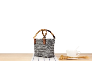 Detail of woven retro tote bag featuring bamboo handle and vintage texture on wood surface