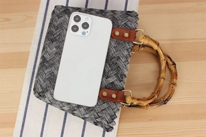 Detailed view of retro woven handbag featuring a natural bamboo handle and metal rivets