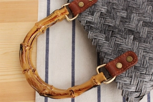 Close-up of bamboo C-handle with gold hardware and woven texture on a handbag