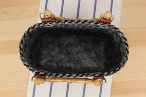 Detailed top view of a woven handbag featuring a natural bamboo handle and metal buckles
