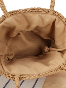 Handcrafted woven straw handbag with interior lining view on a natural wooden surface