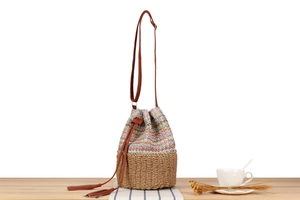 Close-up of a woven bucket bag featuring colorful patterns and brown faux leather drawstring