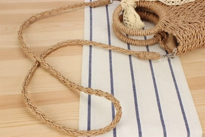 Detailed texture of handwoven straw bag with lace bow and metal strap clips