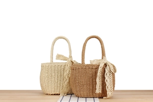 Detail of handmade woven paper rope bags with lace bows in beige and tan colors