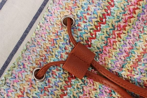 Detail of colorful woven handbag featuring brown leather drawstring and silver metal eyelets