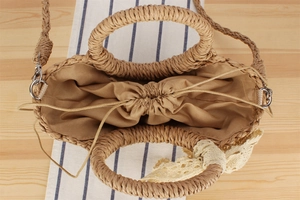 Top view of woven straw beach bag featuring drawstring lining and lace flower detail
