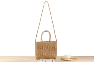 Detail of woven straw tote bag with metallic threads on a natural wooden surface