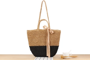 Detail of bohemian paper straw tote bag with black stripes and decorative pink ribbon