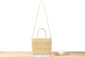 Detail of hand-woven beige straw tote bag with round handles and natural texture