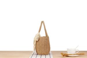 Detail of handmade woven straw bucket bag with elegant white lace ribbon decoration