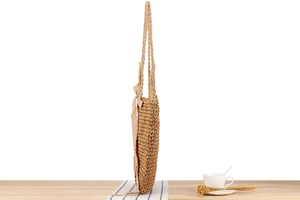 Detail showing the intricate woven paper rope texture and silk bow of the shoulder bag