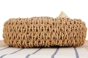 Macro view showing the tight spiral weave detail of a natural straw beach tote bag