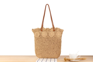 Detail of woven straw bag showing texture, brown leather straps and silver metal rings