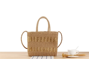 Close-up of woven straw handbag with gold metallic stripes and round handle for summer