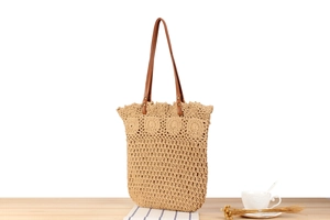 Detail of a beige handmade crochet tote bag with wavy edges and brown leather handles