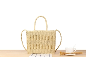 Detail shot of the woven straw tote bag with wave patterns and a sleek shoulder strap