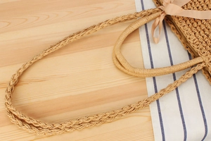 Detail of bohemian paper rope woven beach bag with satin bow and dual strap texture