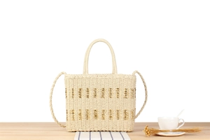 Detail of beige woven tote bag featuring gold metallic texture and dual straps