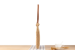 Side view of large capacity woven tote bag with brown leather strap on white background
