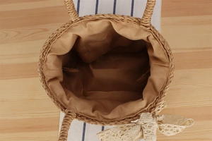 Detail view of woven paper rope bag with inner lining and delicate lace bow accent